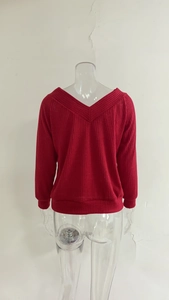 Detail of red V-neck knit sweater showing ribbed texture and elastic cuffs on sleeves