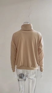 Detail view of apricot ribbed knit sweater featuring drop shoulder and turtleneck back