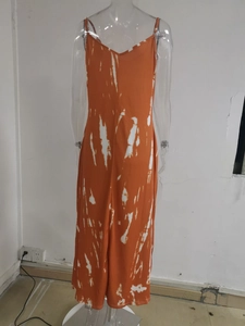 Detailed close-up of orange tie-dye pattern on woman's slit maxi dress with thin straps