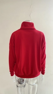 Detail view of red ribbed turtleneck knit sweater showing the back texture and hem finish
