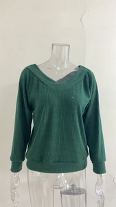 Close-up of dark green V-neck sweater showing ribbed knit texture and cuff details