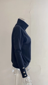 Detailed view of striped knit sweater sleeve featuring silver decorative metal buttons