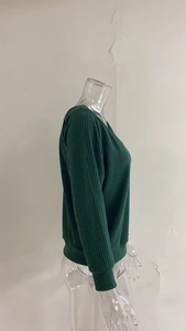 Detail of dark green ribbed knit texture and cuff stitching on long sleeve sweater