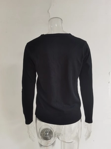 Detail van de geribbelde manchetten en zoom op een zwart gebreid vest met lange mouwen