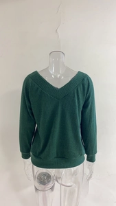 Detail of V-neck dark green ribbed knit sweater showing fabric texture and ribbed cuffs