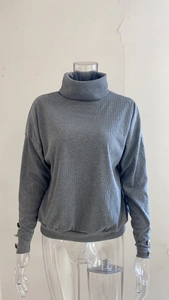 Close-up of grey ribbed knit sweater featuring three silver decorative buttons on the cuffs