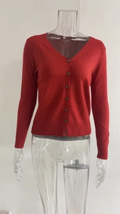 Detail van rood gebreid vest met V-hals, enkelrijige knopen en geribbelde manchetten