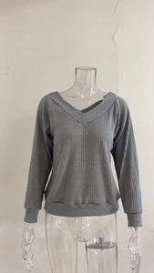 Close-up of a charcoal grey V-neck knit sweater showing ribbed texture and cross-neck detail