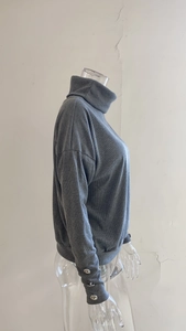 Detail view of grey ribbed knit sweater featuring decorative silver buttons on cuffs