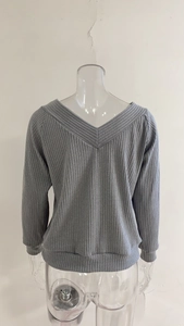 Detail of grey ribbed knit long sleeve sweater with V-back design and ribbed cuffs