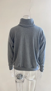Detail view of dark grey high neck knit sweater back with ribbed texture and ribbed cuffs