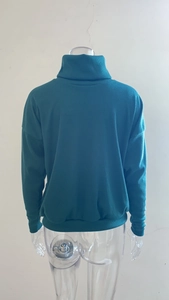 Detail view of the ribbed knit texture and high collar on this dark green oversized sweater
