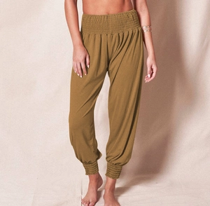 Detail of high-waist smocked elastic band and tapered ankle cuffs on harem pants