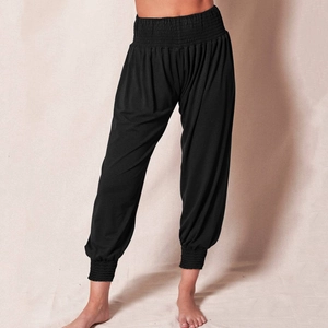 Detailed view of elastic gathered high waistband and pleated fabric of black harem pants