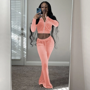 Detail of coral pink velvet two-piece set featuring cropped zip hoodie and flared trousers