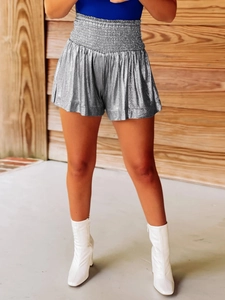 Detail of silver metallic high-waisted shorts with pleated texture and smocked waistband