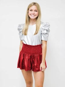 Close-up of shiny metallic red skirt with elastic high waist and silver puff sleeve top