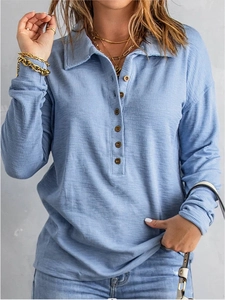Détail du polo bleu clair en maille gaufrée montrant le tissu et les boutons en bois