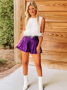 Detail of white feather-trimmed top paired with purple metallic shiny shorts for women