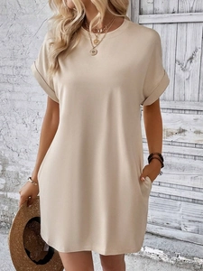 Dettaglio dei polsini arrotolati e tasche laterali su un abito T-shirt beige ampio