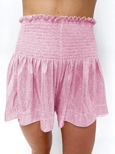 Detail of high-waisted pink shorts with smocked elastic waistband and ruffle trim edges