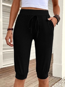Close-up of women's black capri pants with high waist drawstring and side pocket detail
