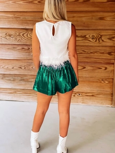 Detail view of metallic dark green shimmering shorts with feather-trimmed white sleeveless top