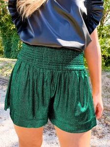 Detail of dark green shimmering shorts with elastic high waist in natural sunlight