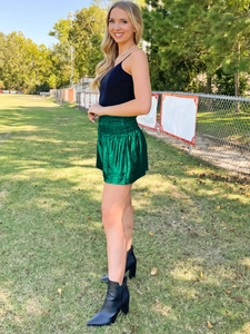 Outdoor shot of shimmering green metallic high-waisted sports shorts with elastic waistband