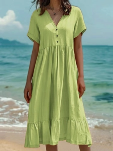 Détail de texture de la robe en lin vert clair avec col en V et boutons noirs à la plage