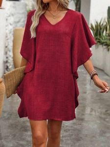 Detail showing wine red V-neck dress fabric texture and ruffle sleeves in sunlight