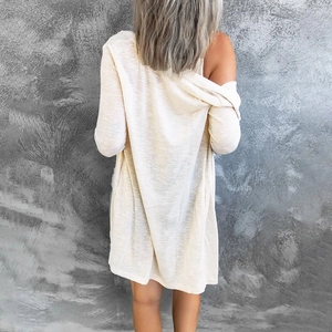 Back view of a loose beige knit cardigan with a textured long sleeve design and casual fit
