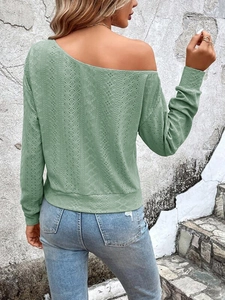Detailed macro view of light green long sleeve top with eyelet pattern texture