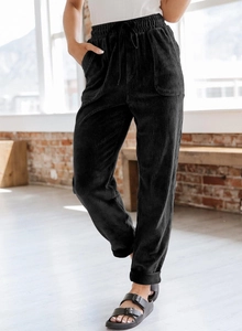 Detail of black corduroy wide-leg pants featuring elastic drawstring waist and side pockets