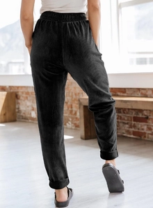 Detail view of high-waist black corduroy trousers with elastic waistband and folded cuffs