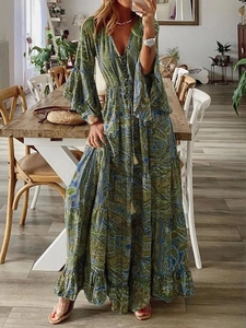 Bohemian paisley print maxi dress with V-neck and flared bell sleeves in a casual home setting