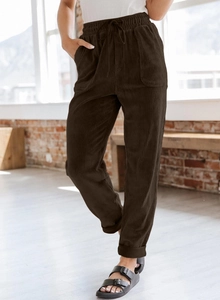 Detail of brown corduroy trousers featuring elastic drawstring waist and side pockets