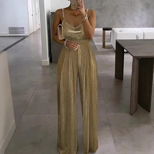 Detail of elegant gold wide-leg jumpsuit with pearl straps and sparkly sequin fabric