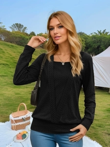 Detailed close-up of a black long-sleeve shirt featuring vertical wavy textured knit fabric