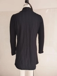 Detail of cable knit pattern on the back of a black long-sleeved cardigan jacket