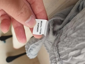 Detail of gray textured knit fabric with care label showing polyester and spandex blend