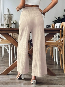 Detail view of high waisted beige wide leg trousers with vertical pleated texture