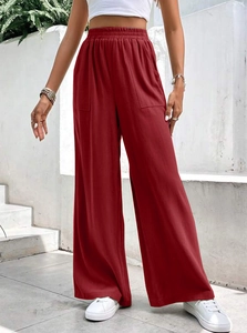 Dettaglio dei pantaloni a gamba larga rosso scuro con vita alta elastica e tasche laterali