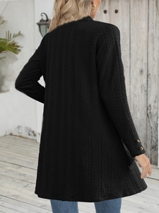 Detail of black knit cardigan texture and decorative buttons on the sleeve cuffs