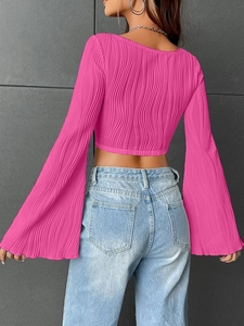 Primer plano del top corto plisado rosa fucsia con mangas acampanadas y tejido texturizado