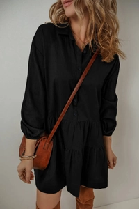 Détail d'une robe chemise noire à manches longues avec ourlet à volants et boutonnage avant