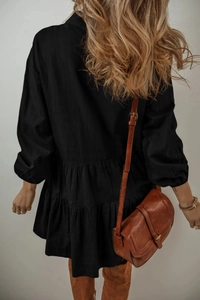 Détail d'une robe noire à volants et manches longues avec un sac bandoulière en cuir