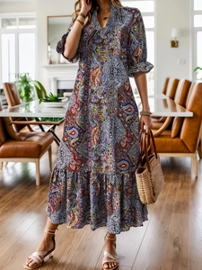 Détail d'une robe maxi à imprimé paisley, col en V, manches bouffantes et jupe à étages