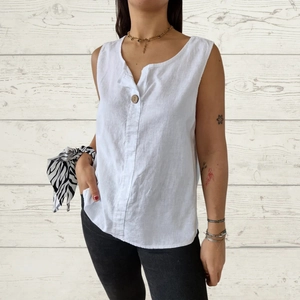Detail of white cotton linen tank top with V-neckline and decorative wooden button