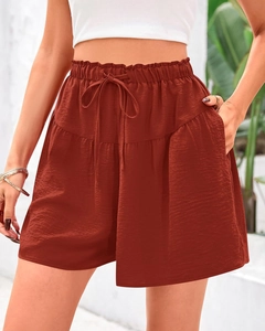Détail d'un short d'été taille haute rouge rouille avec tissu texturé et poches latérales